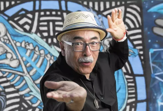 Juan Felipe Herrera in front of a colorful mural background