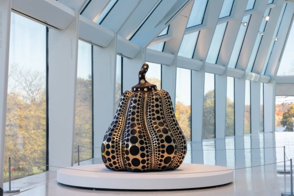 Installation view of a sculptural pumpkin on a white circular stand