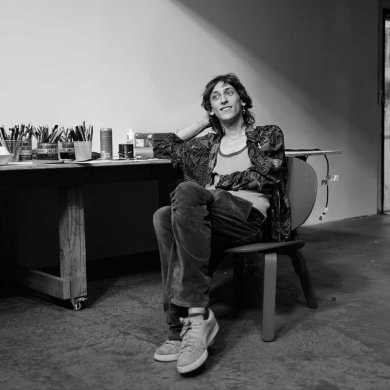 Black-and-white photo of a person sitting in a chair with their legs crossed