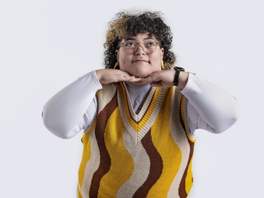 A person smiling with their hands under their chin