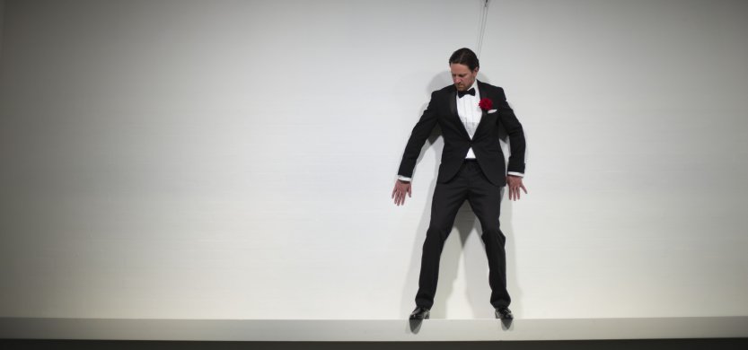 A person in a tuxedo scaling a wall 