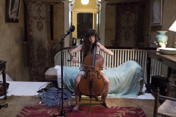 A person playing the cello on a sofa
