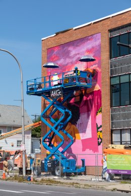 A bright pink mural in progress