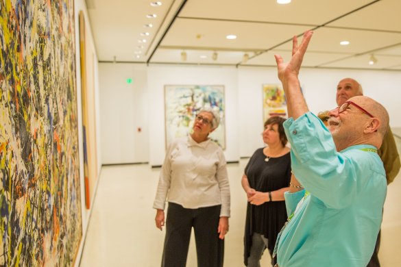 A group of adults on a tour in front of Jackson Pollock's Convergence