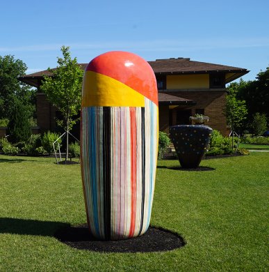 A large sculpture with a red and yellow top and vertical stripes on the bottom two thirds