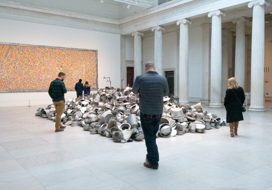 Guests around Subodh Gupta's This is not a fountain, 2011–13, in We the People: New Art from the Collection. Pascale Marthine Tayou's Chalk Fresco A, 2015, is in the background.