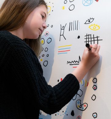 A woman drawing on wallpaper on the wall