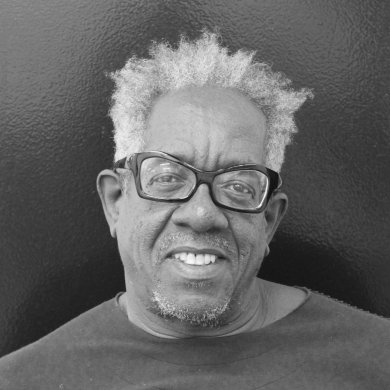 A Black man with glasses smiling at the camera