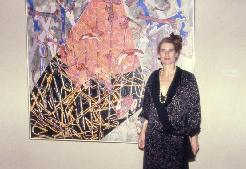 A color photograph of Nancy Graves in front of one of her artworks