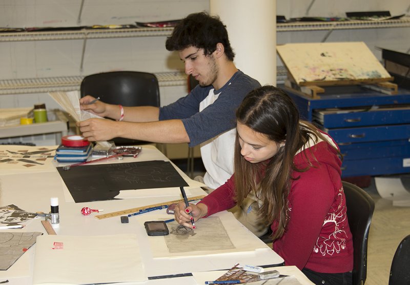 A teen boy and a teen girl making art in the classroom