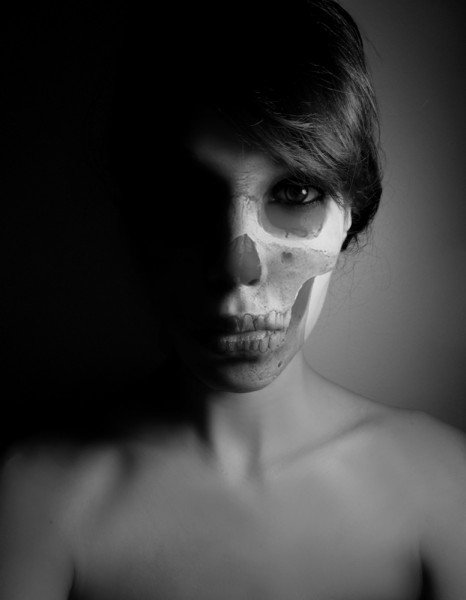 Black and white photograph of a woman's face made up to resemble a skull