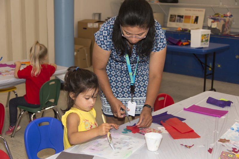 Teacher helping young students make collages in a classroom