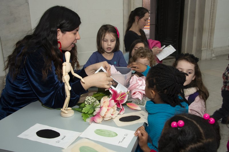 A woman leads children in an activity around the ArtCart