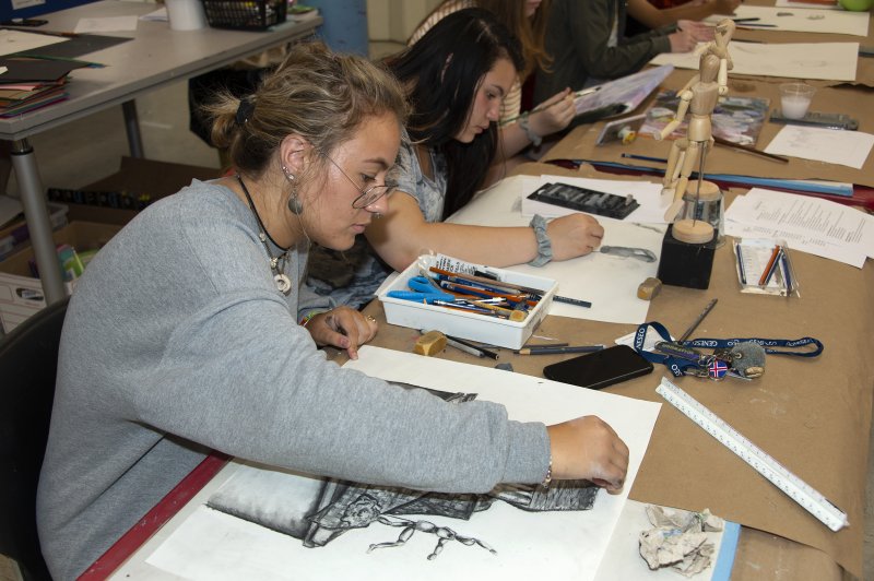Teens creating drawings at a long table
