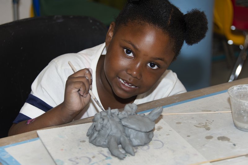 An African American girl working on a sculpture