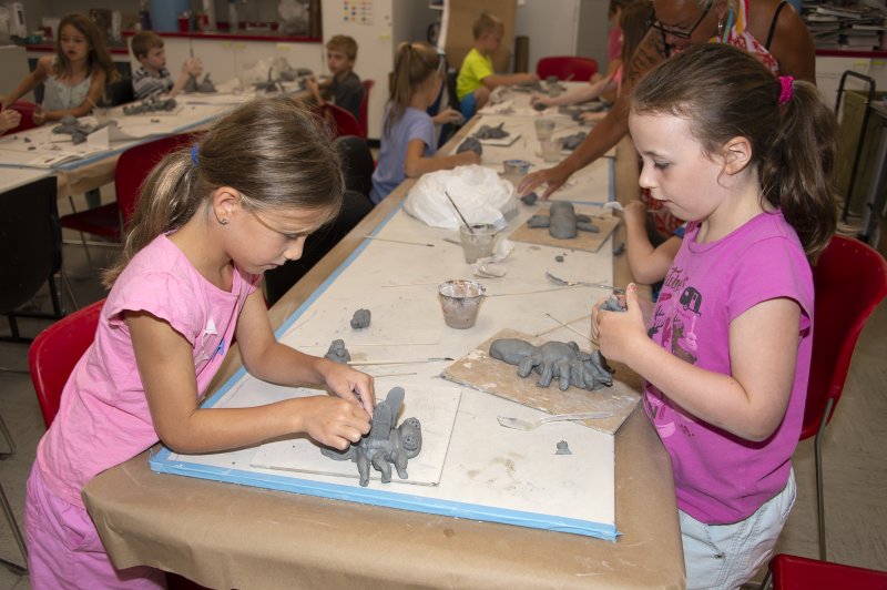 Several children creating clay sculptures of insects