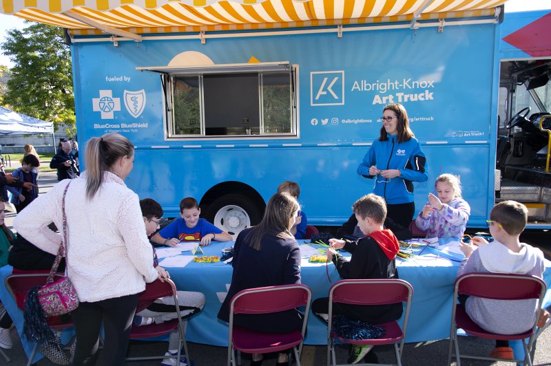 Kids making prints of the art truck in front of a big blue truck