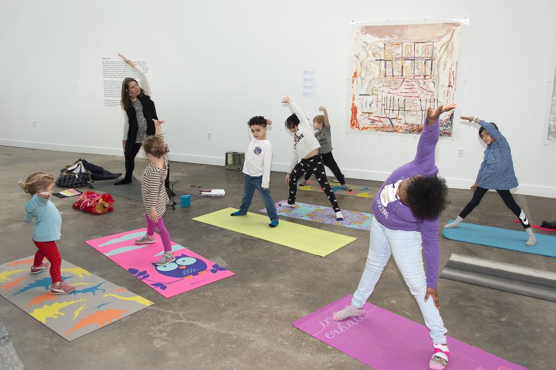 A woman leading a group of kids on yoga mats in a yoga pose