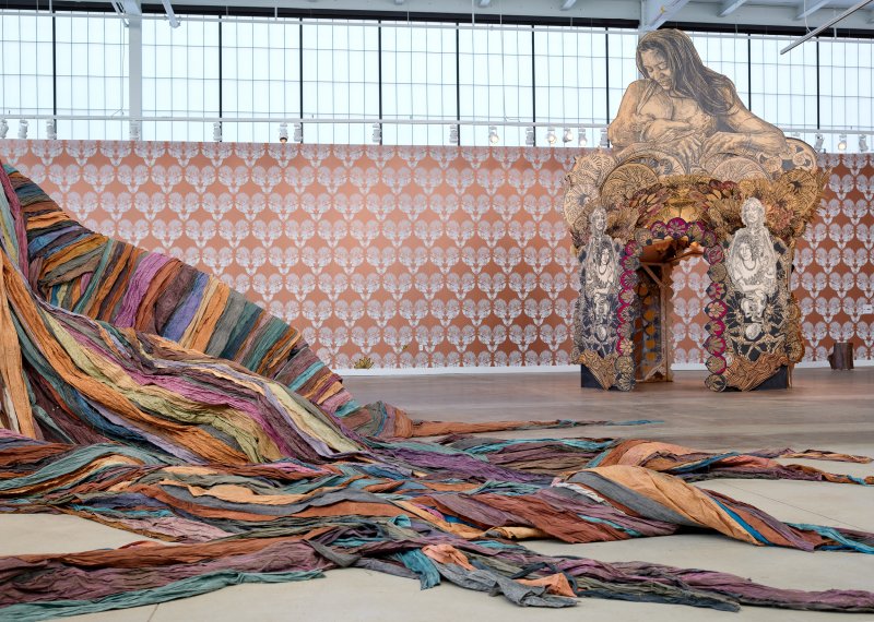 The roots of a large fabric tree sculpture and a temple-like sculpture