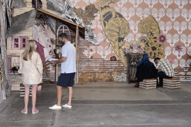 Two people looking at a sculpture and two people sitting on stools