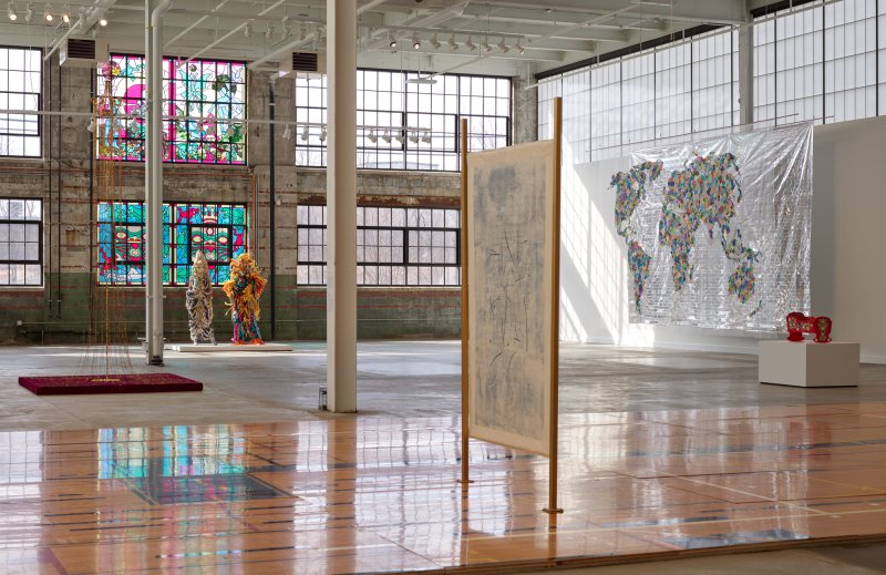 An installation of several sculptures and wall hangings in a large industrial building