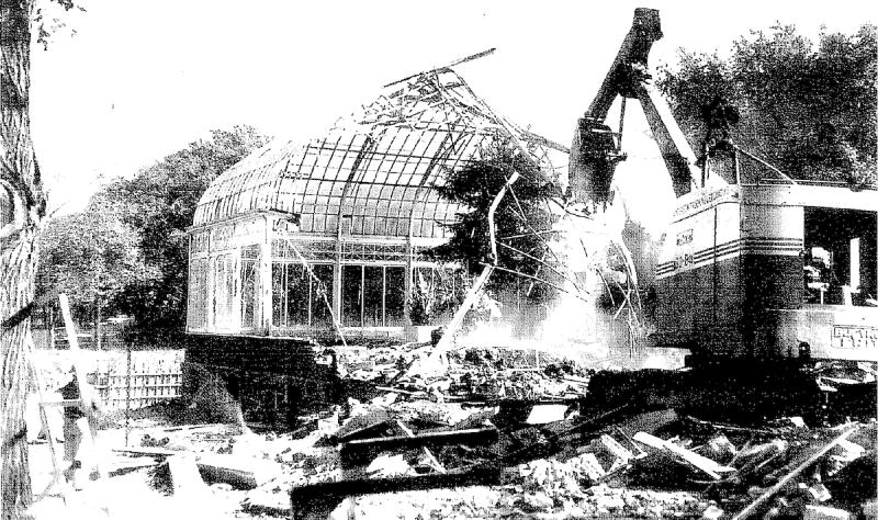 Black and white image shows the demolition of a glass structure