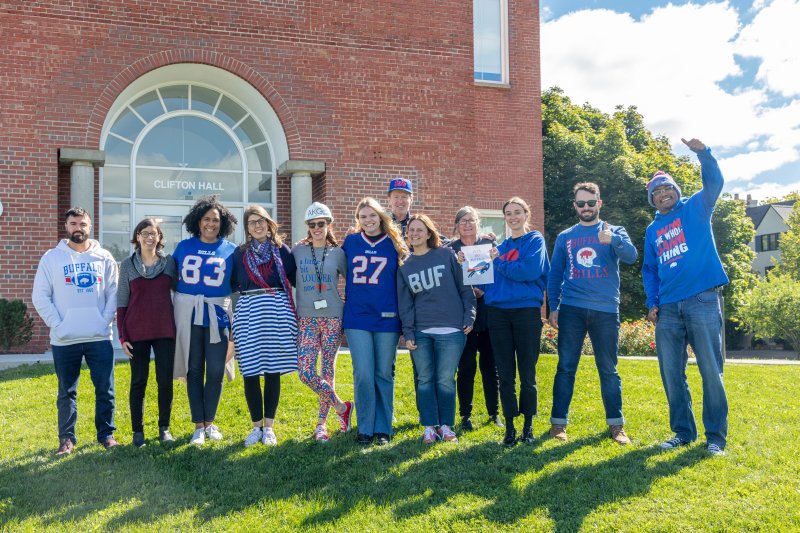 Group of Buffalo AKG staff members posing outside of Clifton Hall in their Buffalo Bills gear 