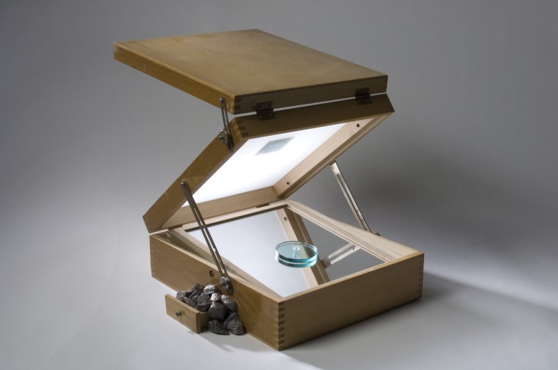 A wooden box opens, lit with a mirror beneath