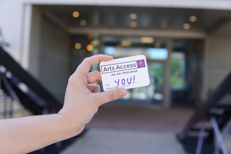 A hand holding a card that says "Arts Access - An ASI Program. YOU!" 