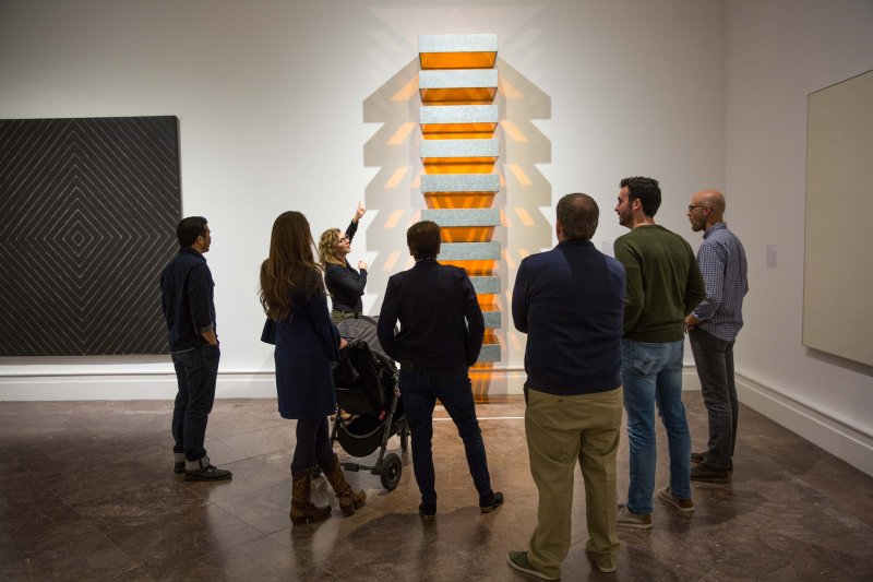 Group of people looking at a large artwork on a wall