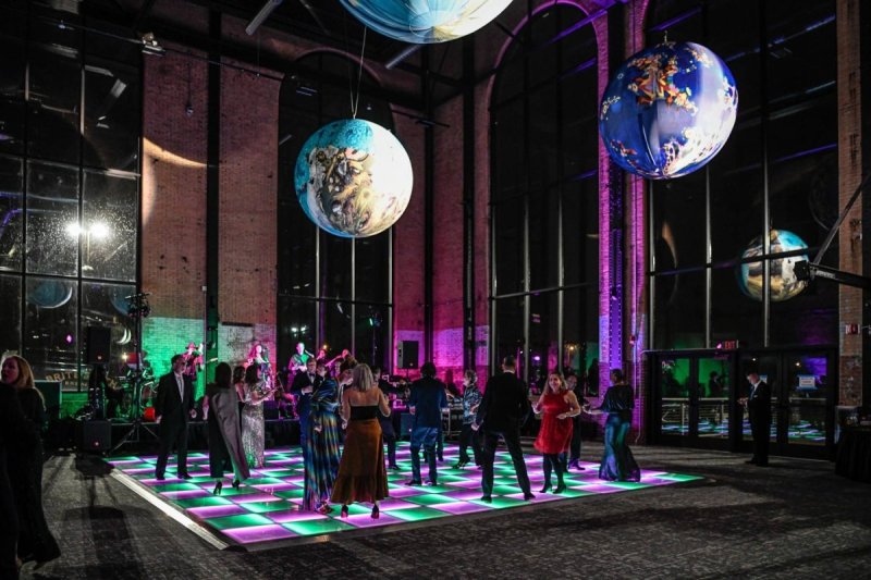 Partygoers on a neon lit dance floor in a dark event space 