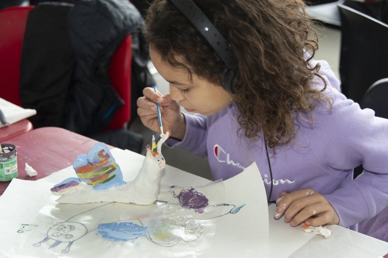 a young girl painting a clay unicorn