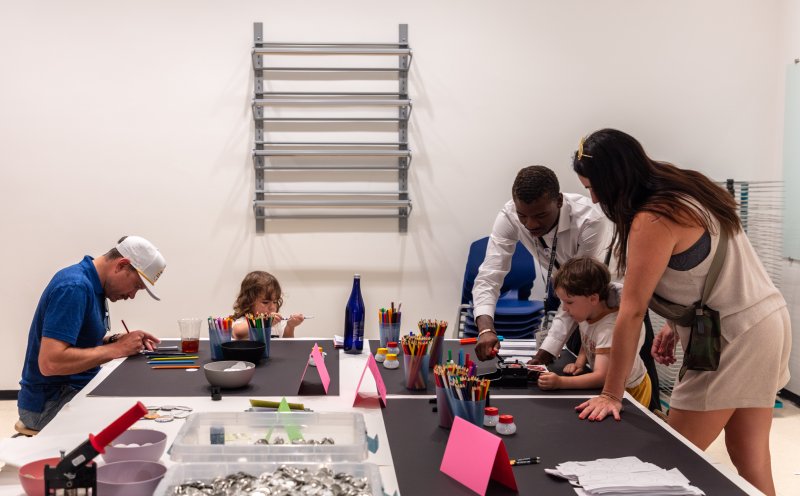 two men, a woman, and two children working on crafts around a table
