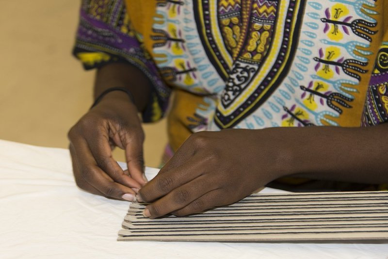 A person's hands working with thread on a paper