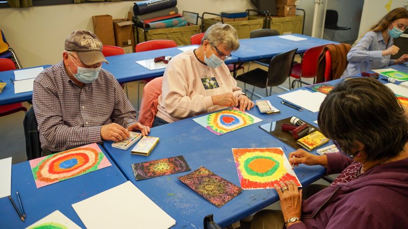 Two women and one man coloring at a table