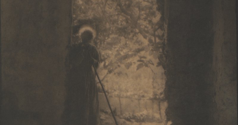 Crop of a sepia toned photograph shows a woman in a darkened doorway, with the bright outdoors beyond
