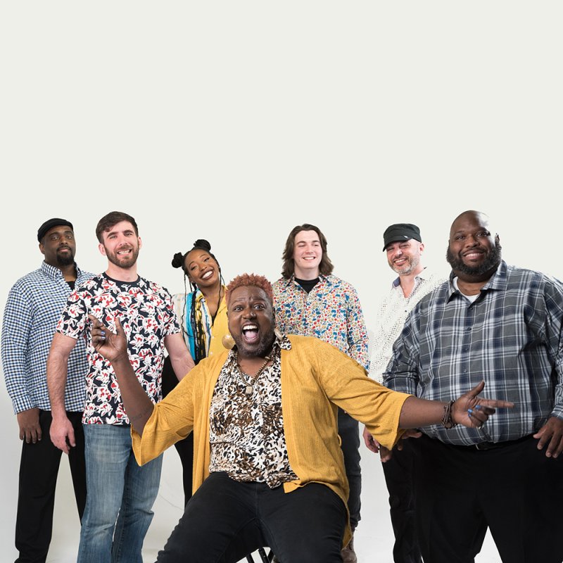 Six men and one woman smiling for the camera in front of a white background