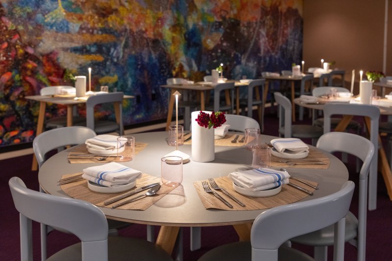 A dining room set up with a colorful mosaic on the back wall