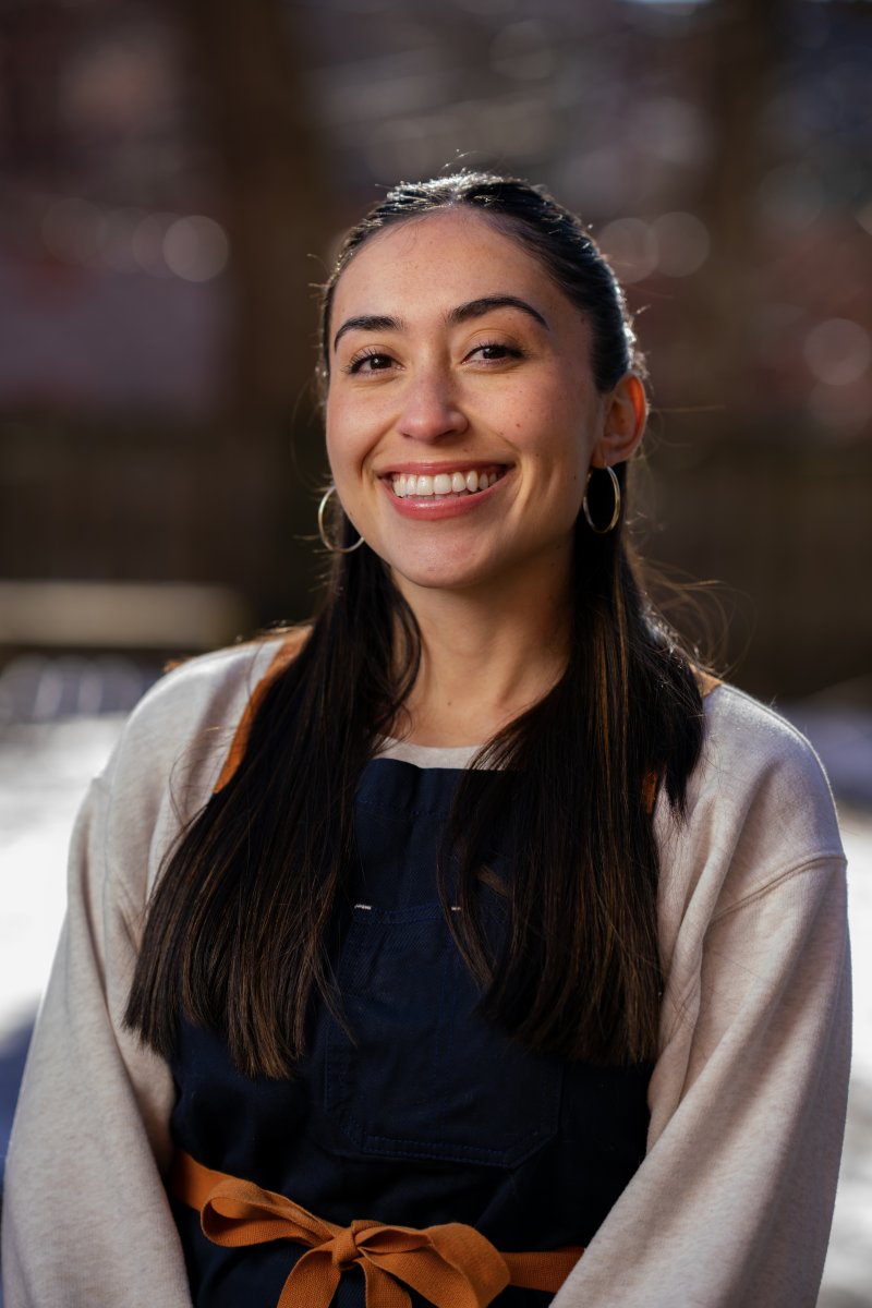 Headshot of a woman with dark hair and a medium skin tone smiling