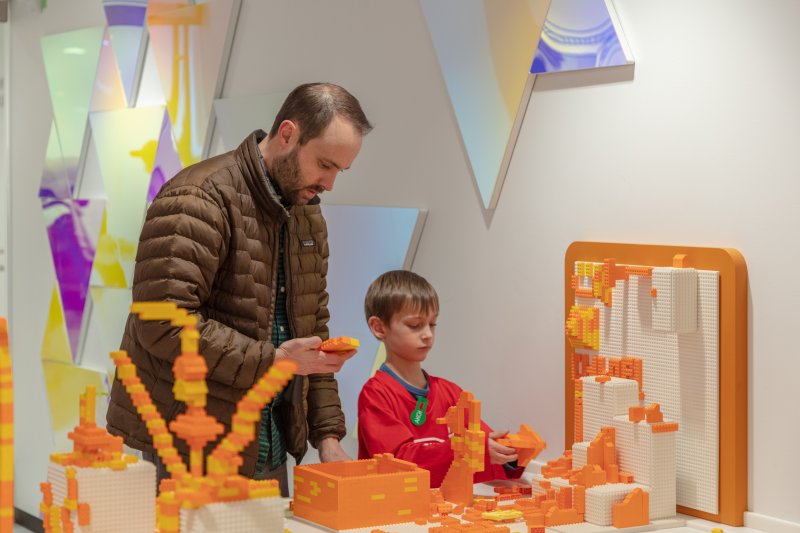 A man with his young son playing with orange legos