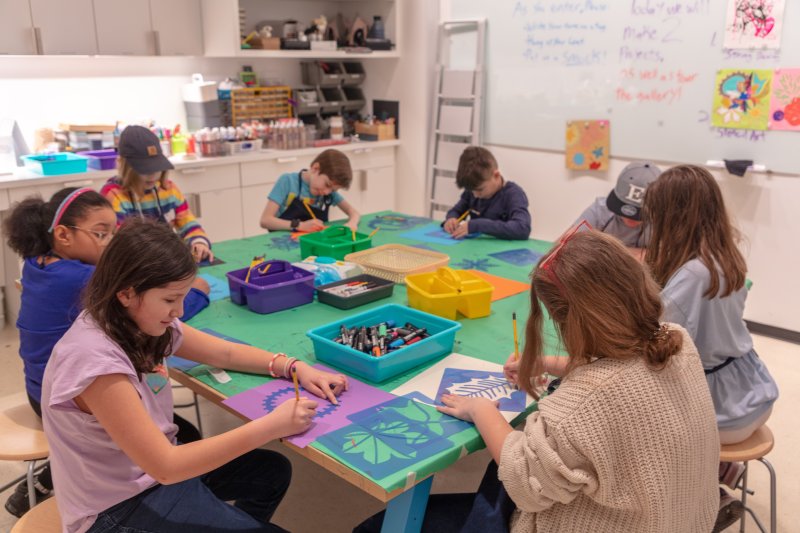 A group of adolescents working on art projects around a green table