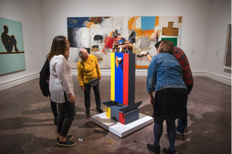 A group of adults examining a sculpture in a gallery