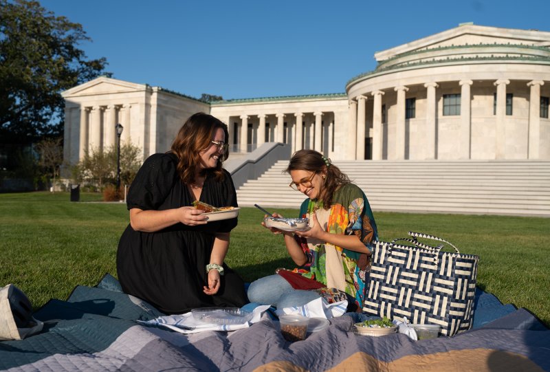 Two women having a picnic in front of a museum