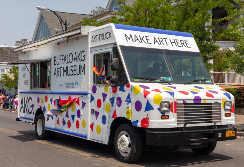 White truck covered in primary shapes in primary colors with the words "Make Art Here" on the front and "Buffalo AKG Art Museum" on the side