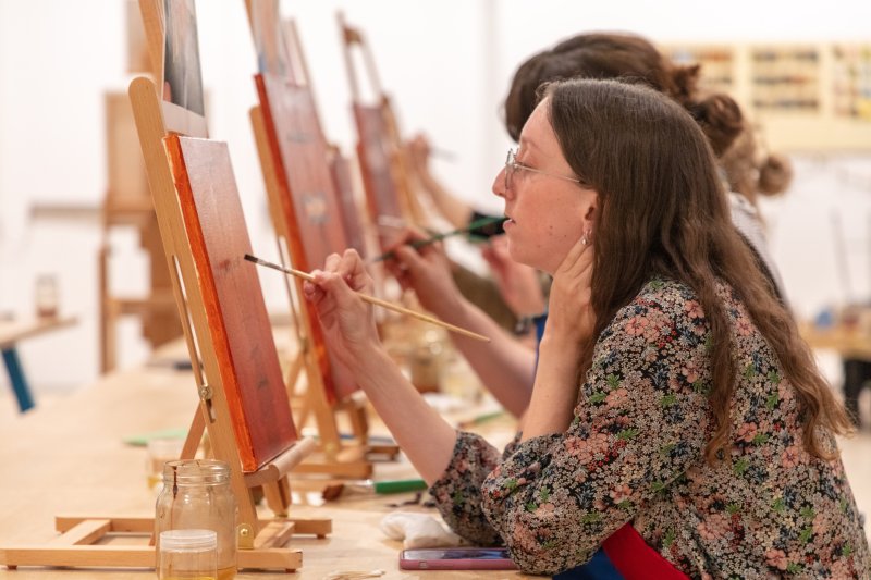 A woman sitting in a class painting
