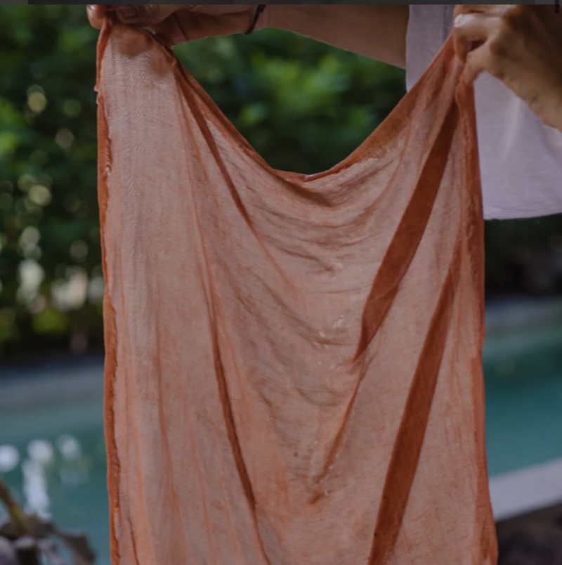 A person holding up a terracotta cloth