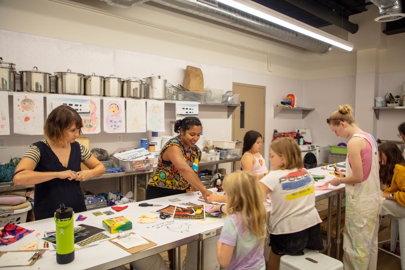 A group of women and young girls working on art projects