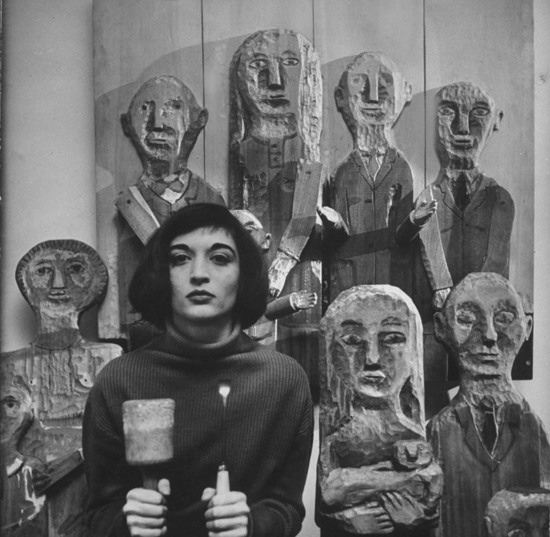 Black-and-white image of Marisol with carved wooden figures