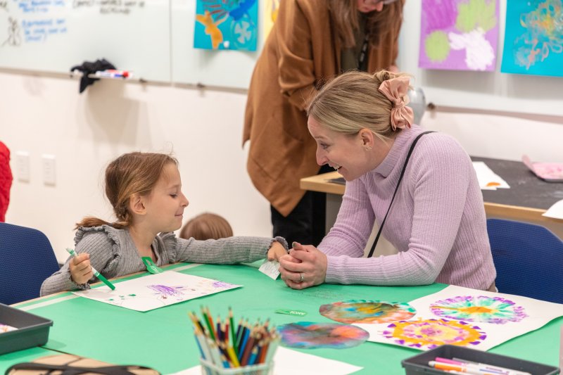 A parent and child smiling at one another while working on a craft