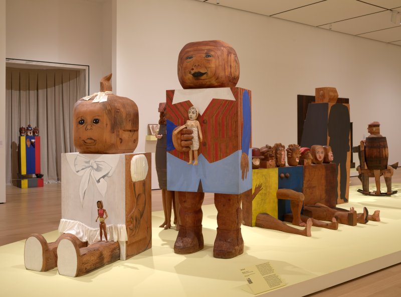 Installation view of two large wooden sculptures of a baby boy and girl